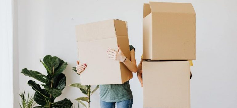 Two persons holding moving boxes